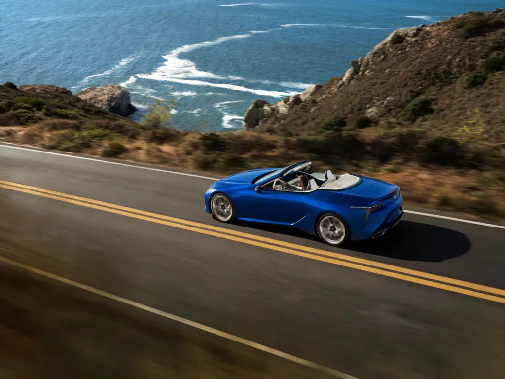 The Lexus LC 500 Convertible driving on a highway along the ocean.