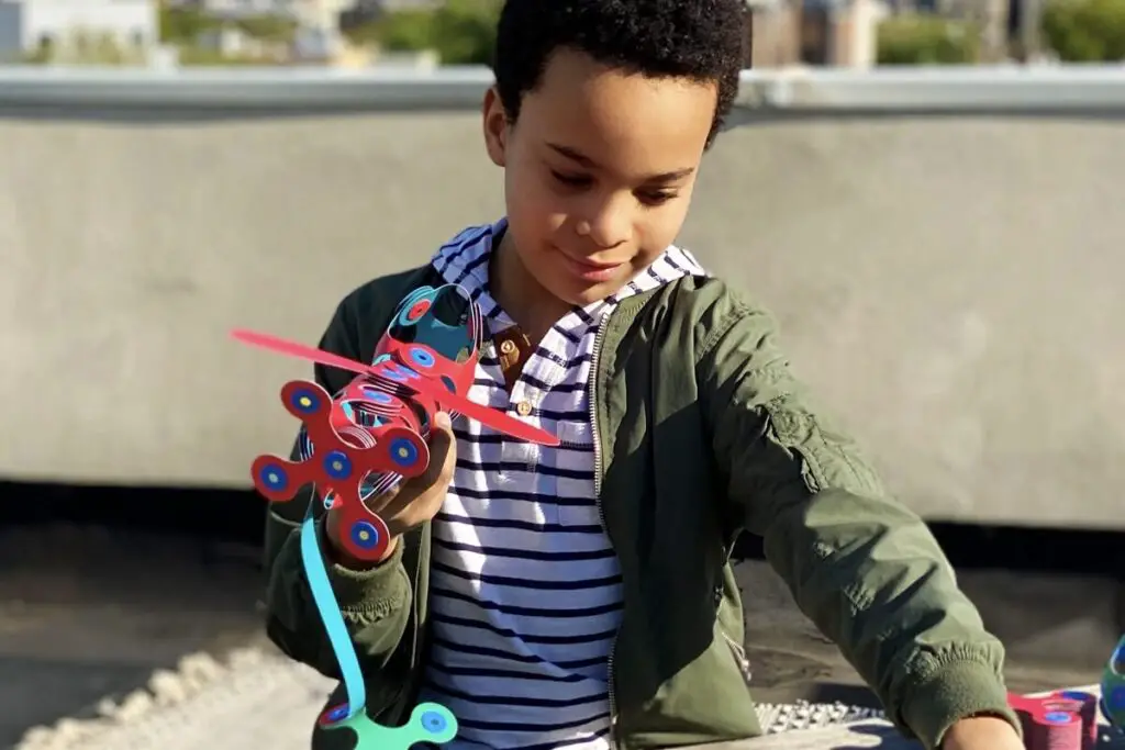 A little boy playing with an airplane made from Clixo pieces.