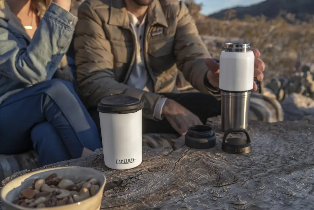 Two people using their CamelBak MultiBev to share outdoors.