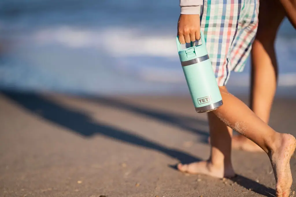 A kid at the beach using the Yeti Rambler Junior water bottle.