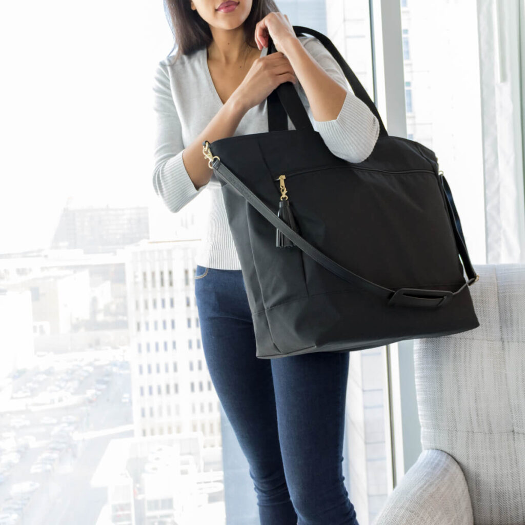 A woman holding her Logan + Lenora Weekender bag.