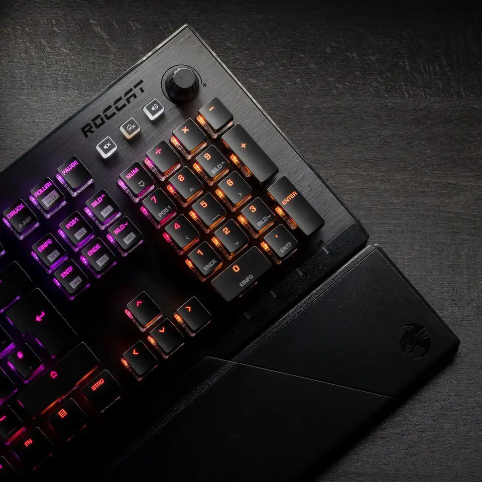 The Roccat Vulcan 121 Aimo gaming keyboard on a desk with its RGB display on.