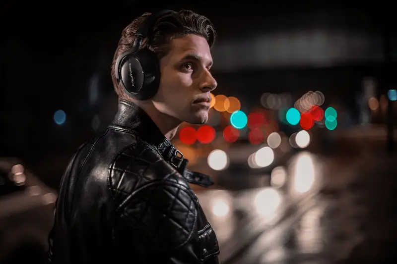 A man wearing his Bowers & Wilkins PX7 Carbon headphones in the city at night.