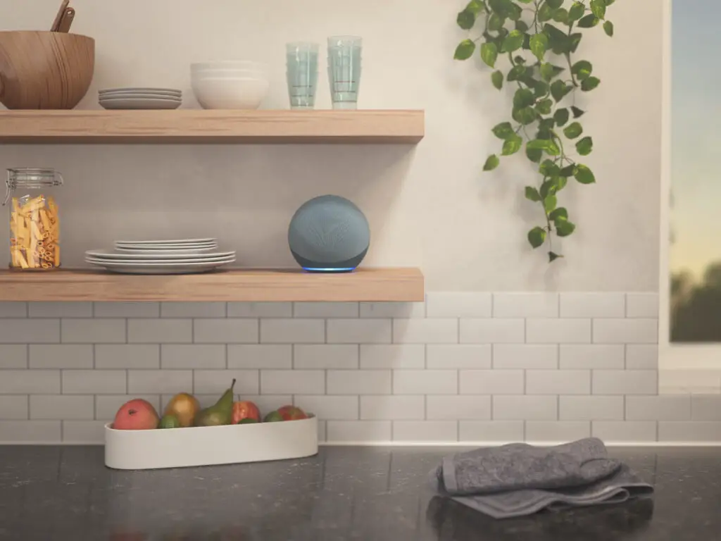 The Amazon Alexa Echo Dot sitting on a kitchen shelf.