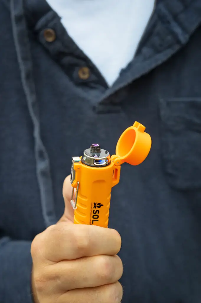 A man holding a SOL fire lite rechargeable lighter.