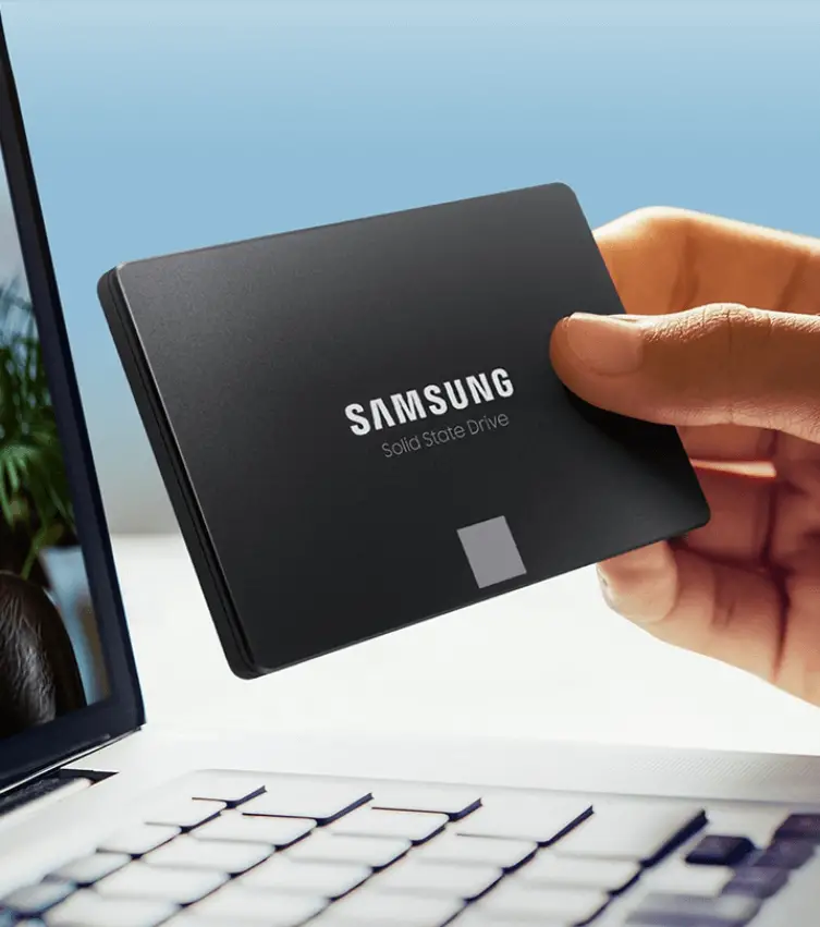 The Samsung 870. EVO Solid State Hard Drive being held in front of a laptop.