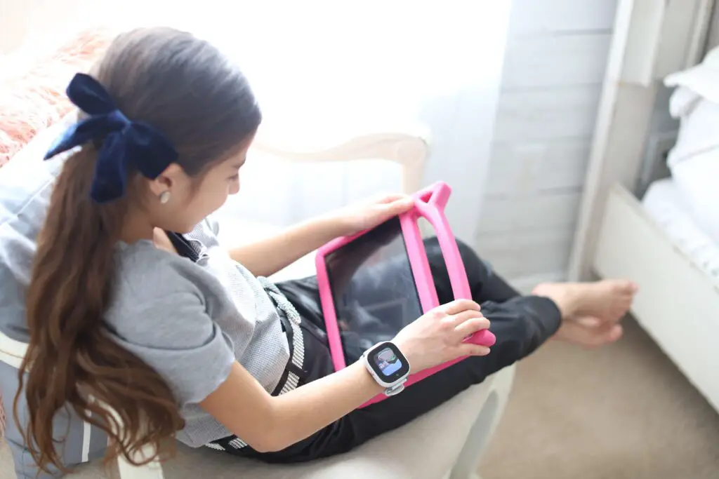 A little girl playing on her tablet wearing the GizmoHub Verizon watch Disney Edition.