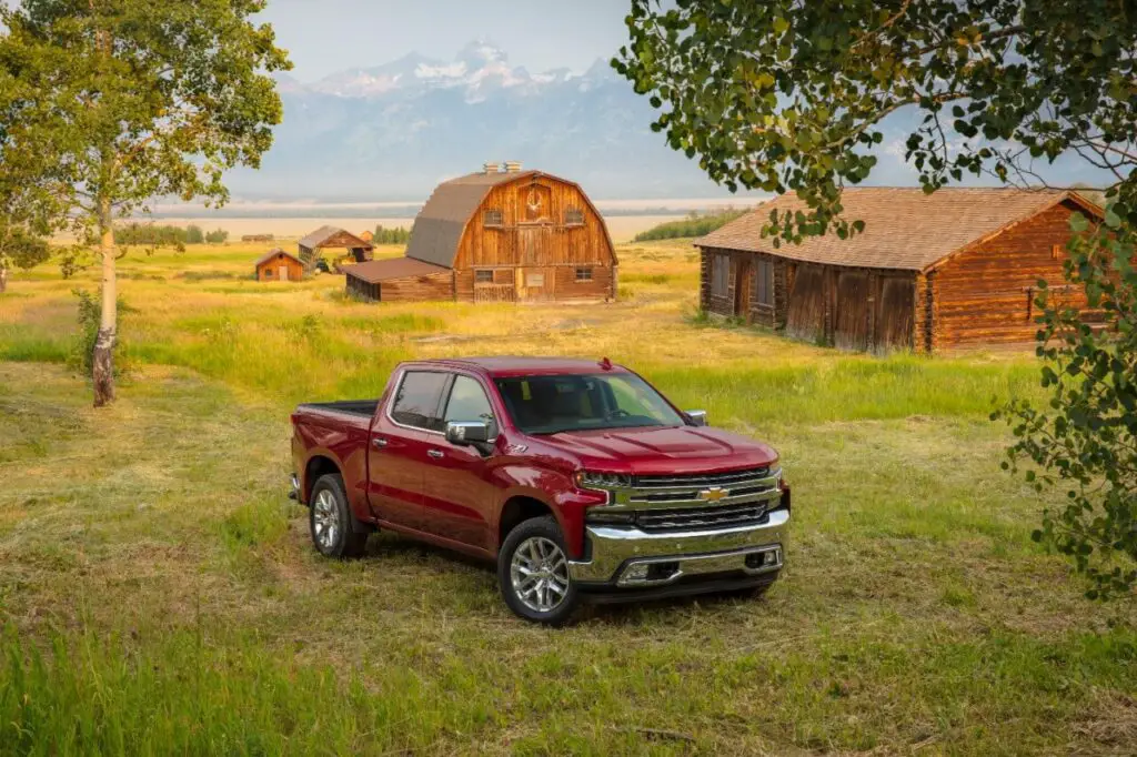 A red 2021 Chevy Silverado 1500 4WD Crew Cab LTZ pickup truck on a beautiful farm next to the mountains.