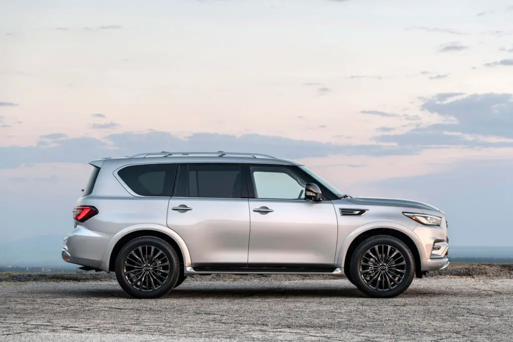 A silver 2021 Infiniti QX80 parked outdoors with a beautiful sky behind it.