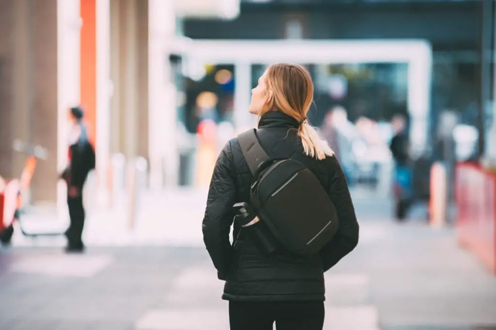 A woman wearing her Navigator Sling 6L from Nomatic as she wanders the city.
