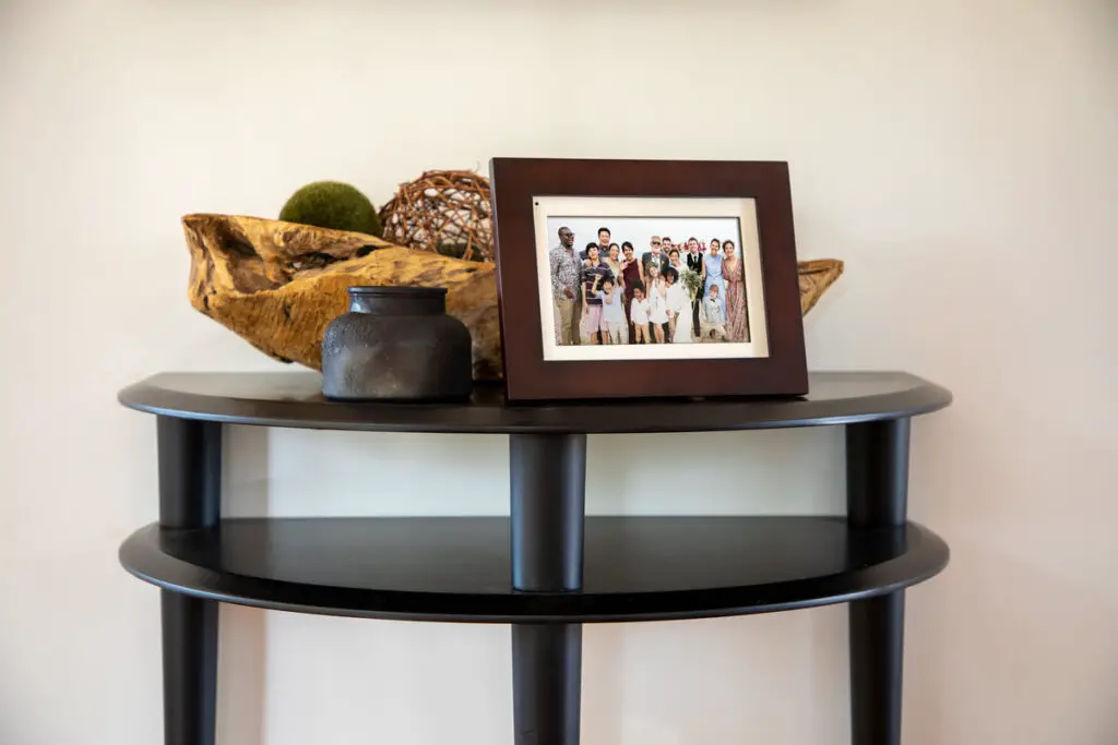 The Simply SmartHome PhotoShare Smart Frame on a decorative table as it displays a large family photo.