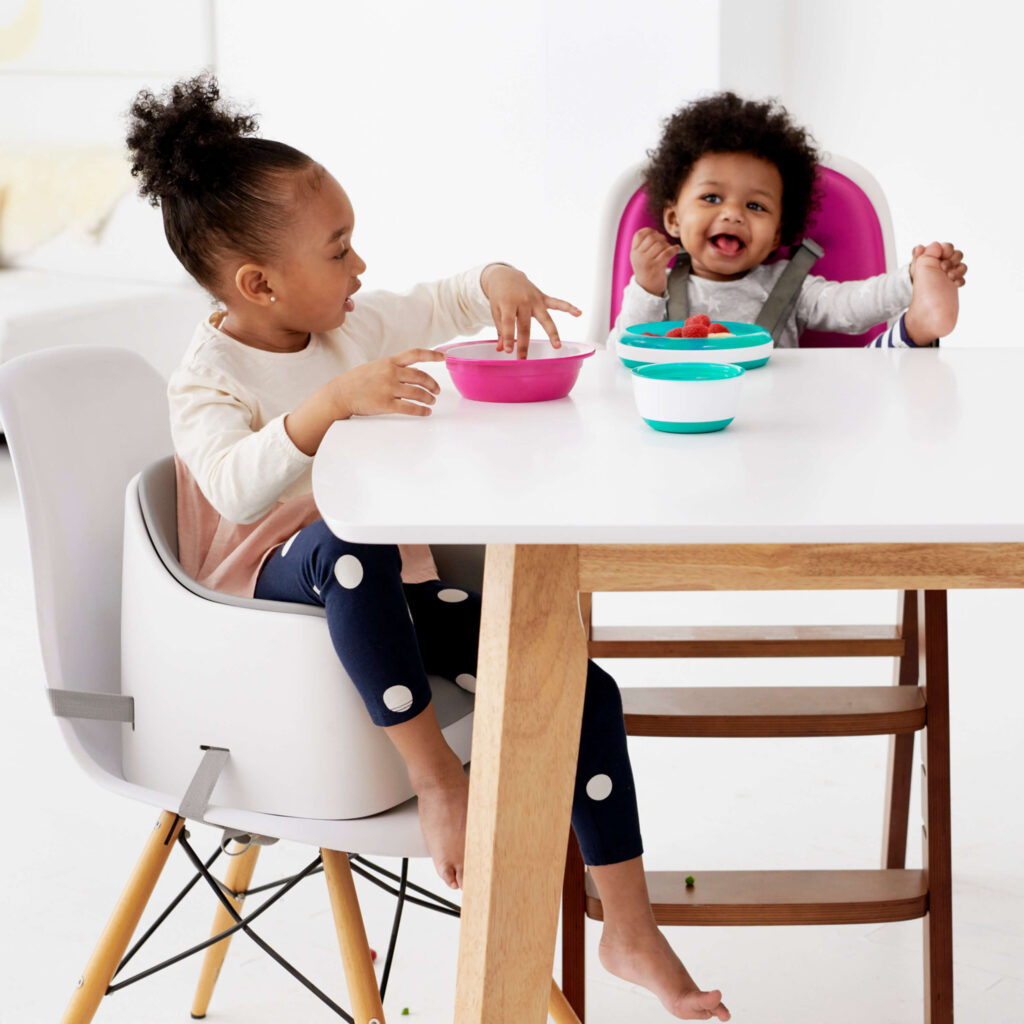 A little girl using her Nest Booster Seat with the removable cushion from OXO as she eats her meal.