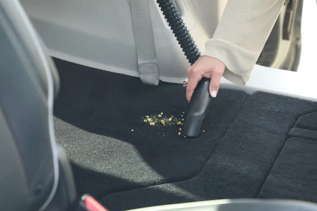 A woman using the Chrysler Pacifica Pinnacle's built-in vacuum to clean up some crumbs.