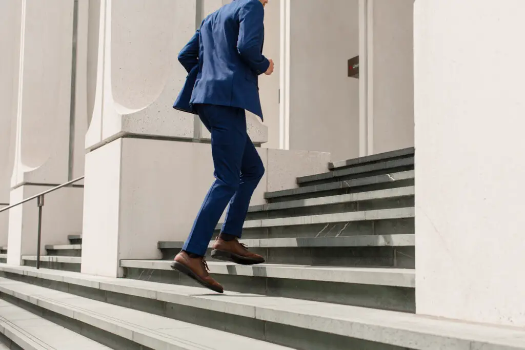 A man wearing his Third Mind shoes as he walks up the steps in a suit.
