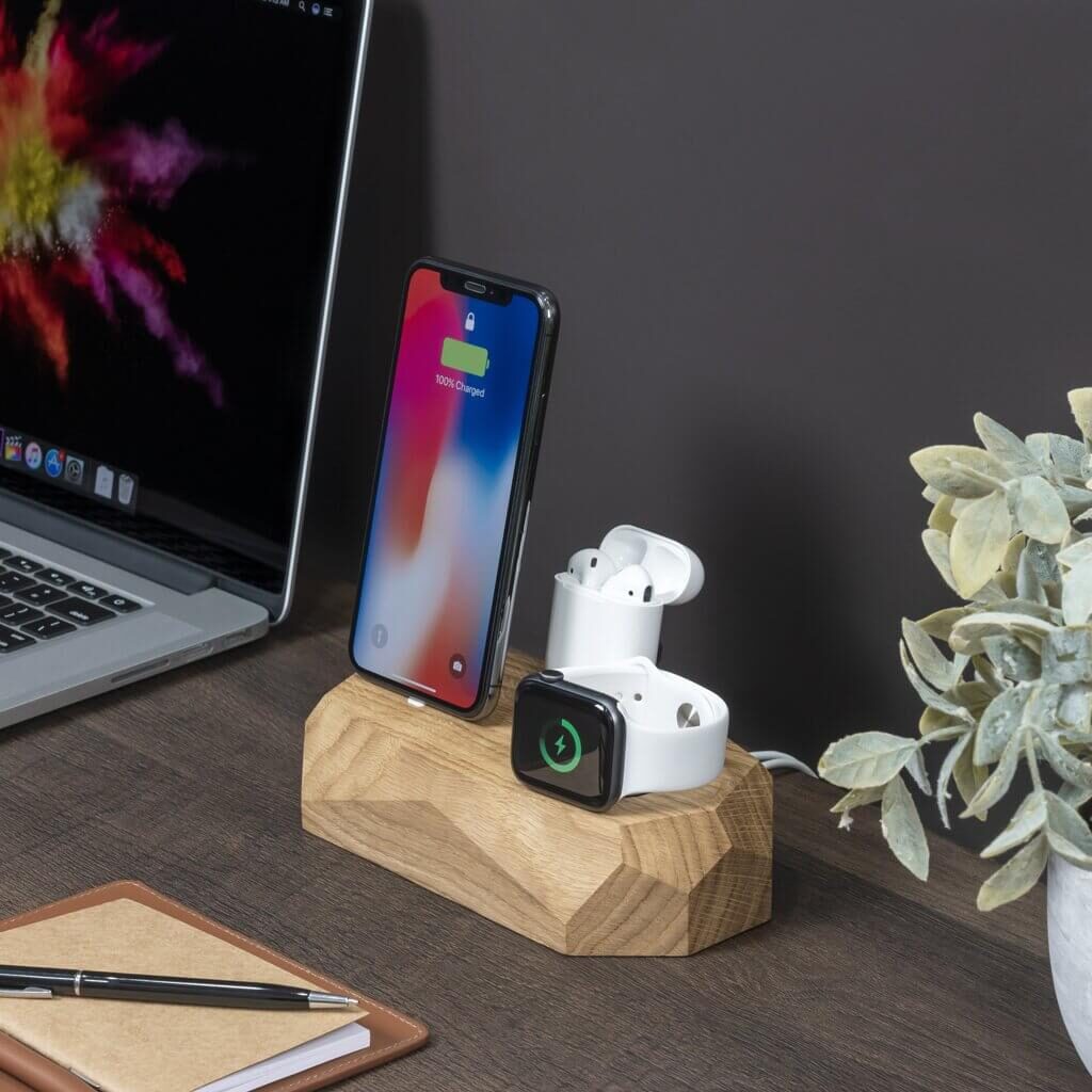 The Oakywood triple dock on a desk in use by AirPods, the Apple Watch, and an iPhone.