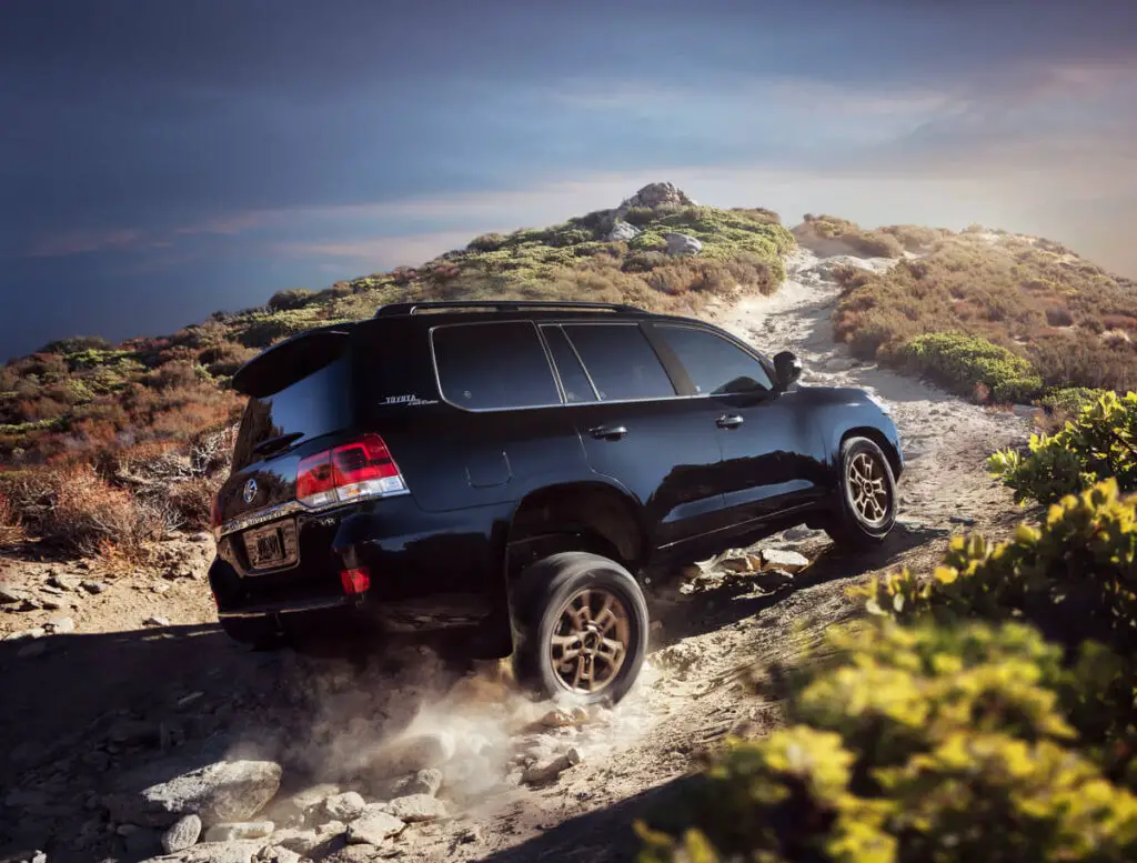 The black 2021 Toyota Land Cruiser Heritage Edition scaling a rocky mountainous path.
