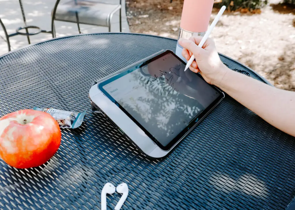 Someone sitting at a picnic table using their iPad Pro while utilizing their Hubble iPad case. 