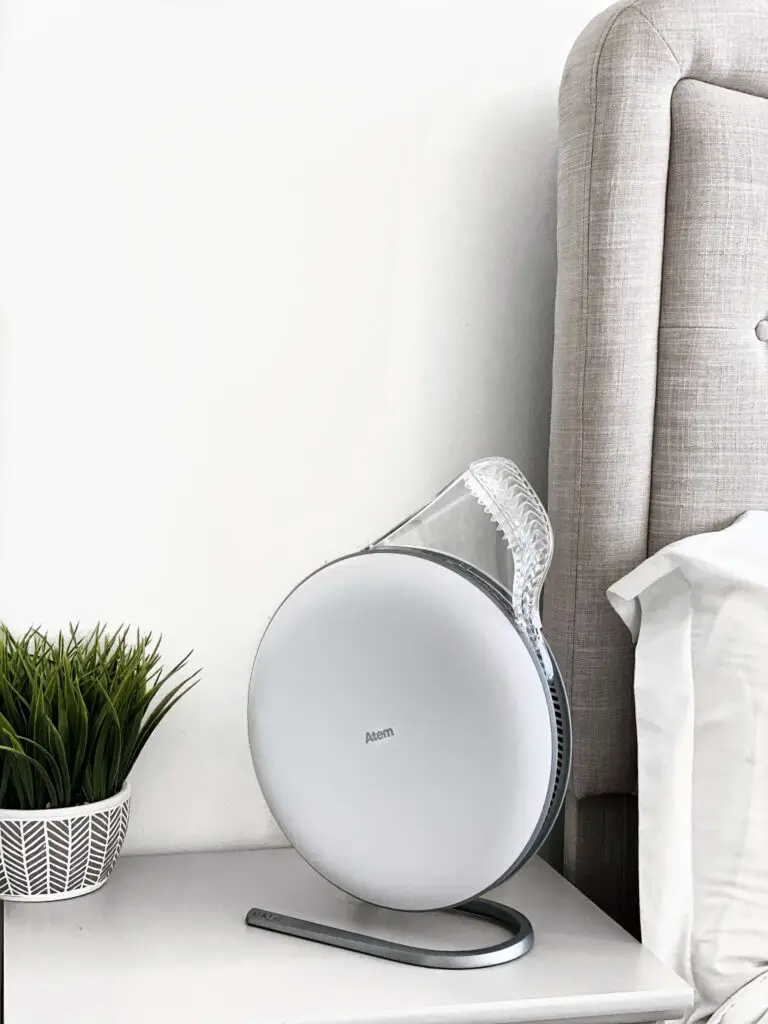 The IQAir Atem personal air purifier on a side table in the bedroom.