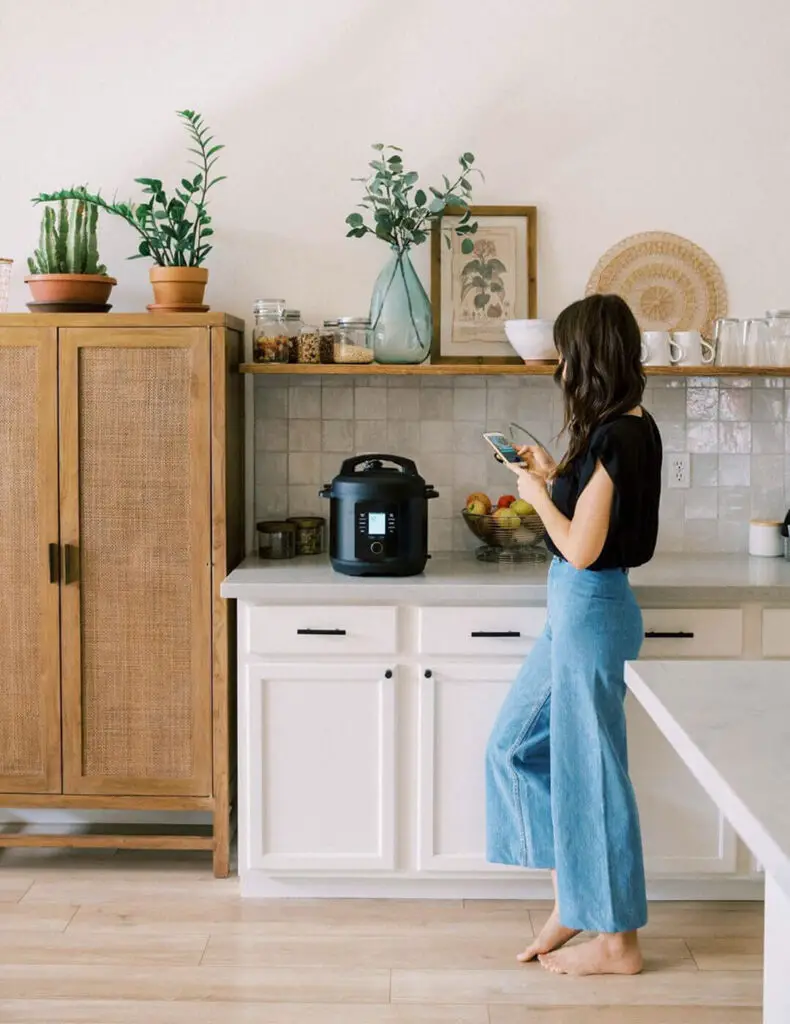 A woman standing in her kitchen using her Chef IQ.