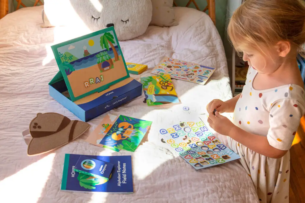 A little girl playing with her Homer Explore Kit on her bed.