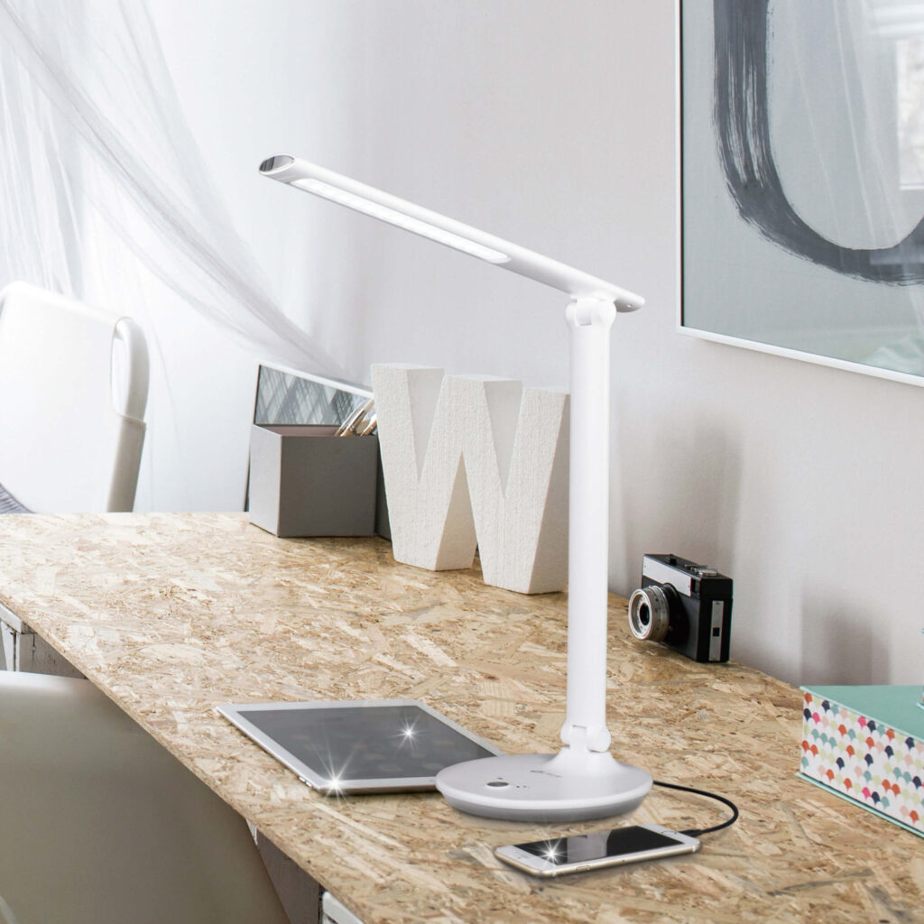 The OttLite lamp on a desk and lit over an iPad and iPhone