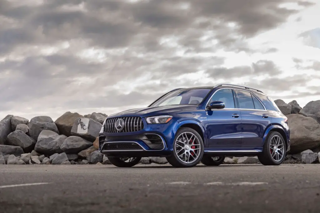 The  blue AMG GLE 63 S Coupe on a road next to a pile of boulders. 