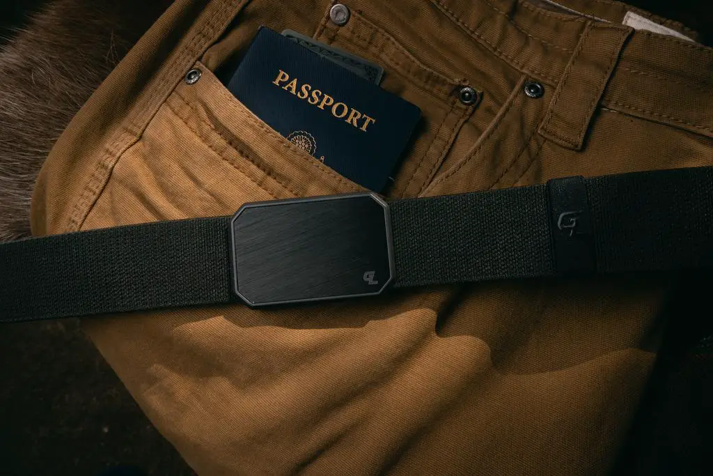 The Groove belt on top of some brown pants with a passport in the pocket.