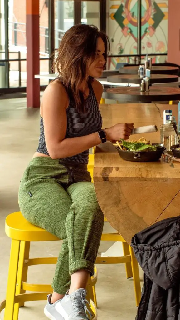 A woman wearing her Evolution Joggers from Coalatree while eating at a restaurant.