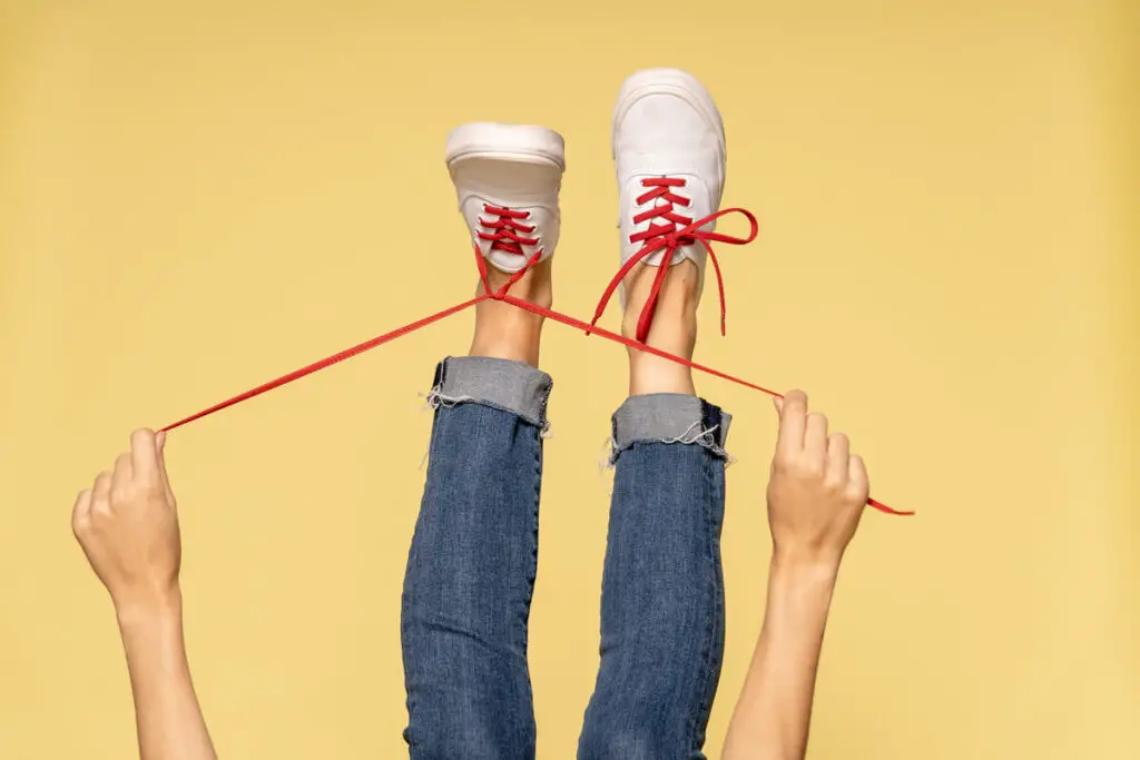 Someone's legs sticking up in the air as they tighten their bright red, Stretchlace shoelaces.