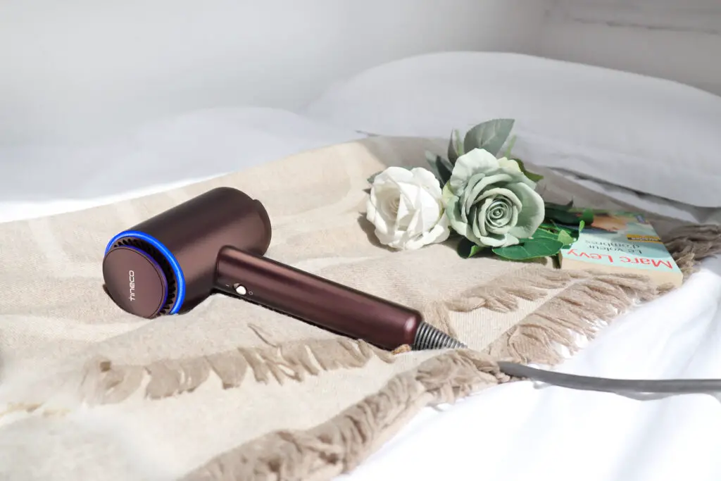 The Moda One blow dryer laying on a blanket with some roses and a book.
