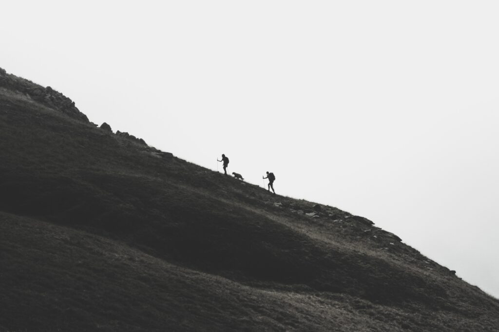 Silhouettes of people hiking on a mountain ridge with their dog as well.