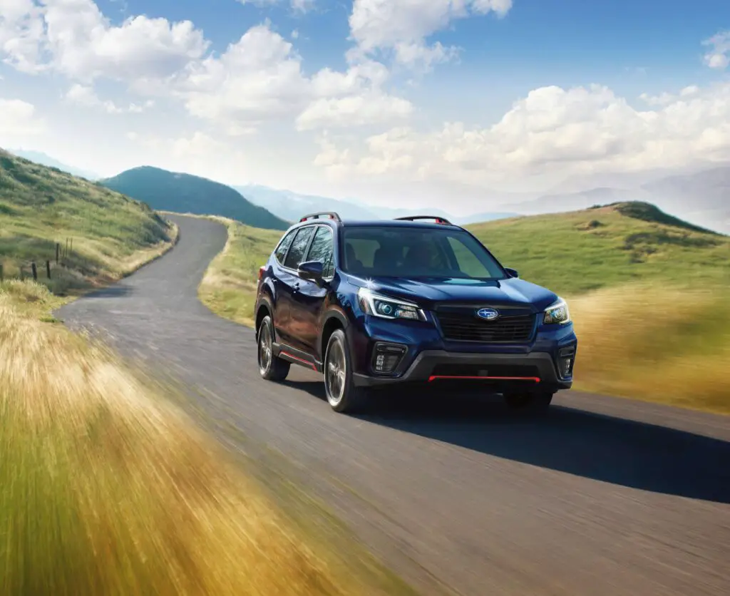 The 2021 Subaru Forester Sport driving down a country road.