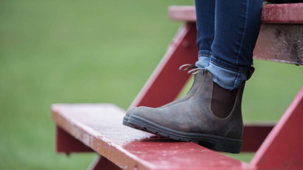 A girl wearing her Blundstone Boots as she sits on a bright red picnic table.