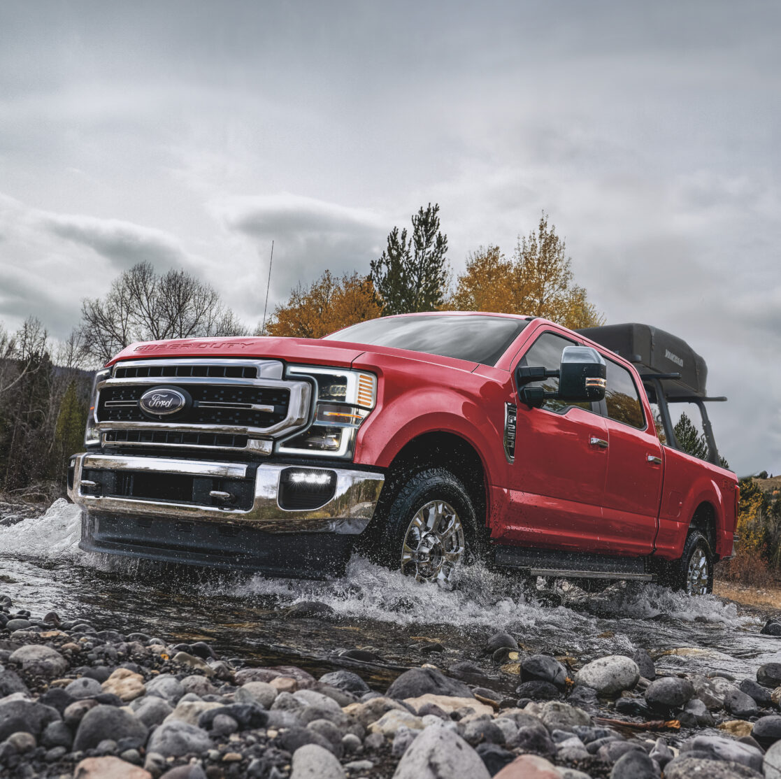 The 2021 Ford. F-250 as it drives through a rocky stream.