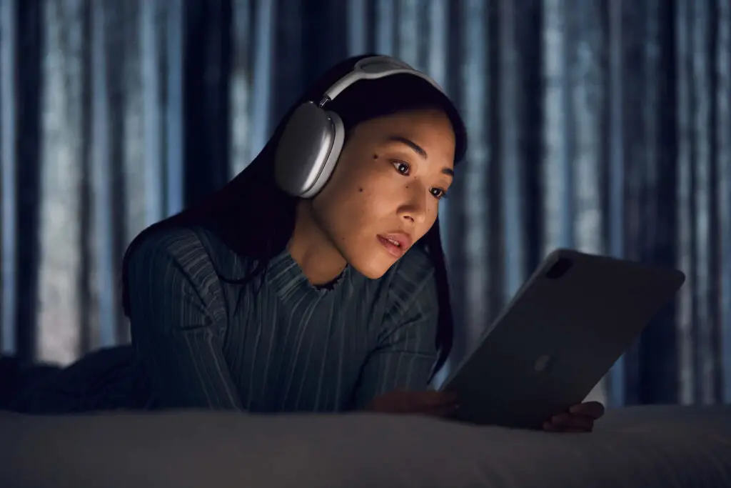 A woman using her iPad while utilizing the Apple AirPods Max.