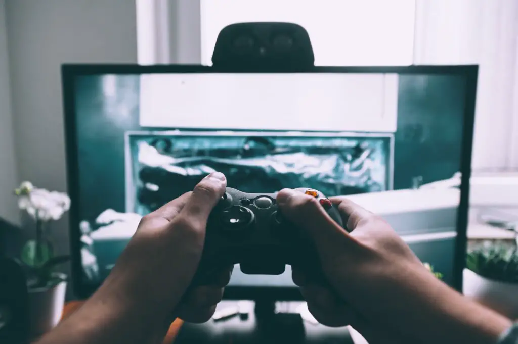 person holding game controller in-front of monitor